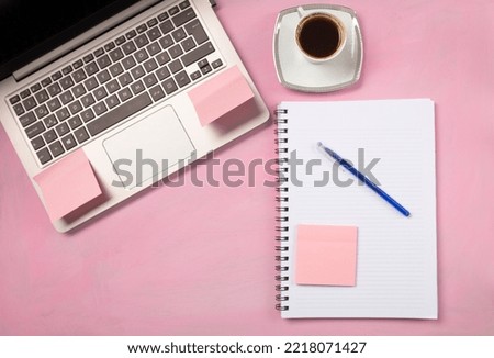 desk, computer and notepad on pink background