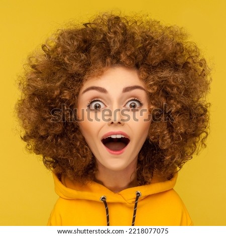 Wow, unbelievable. Comic portrait of shocked surprised funny woman with Afro hairstyle looking at camera with open mouth and amazed big eyes. Indoor studio shot isolated on yellow background. Royalty-Free Stock Photo #2218077075