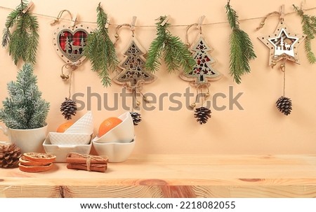 Empty rustic table with a live Christmas tree in a mug, pine cones, cinnamon, kitchen utensils and homemade wooden ornaments. Christmas and new year eco mockup for product design and showcase