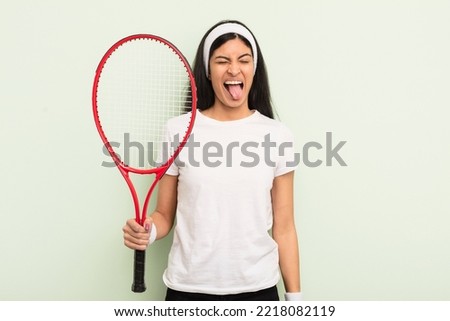 young pretty hispanic woman with cheerful and rebellious attitude, joking and sticking tongue out. tennis concept