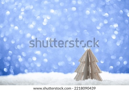 Small wooden Christmas tree on snow and blue bokeh background.Postcard happy new year .Copy space 