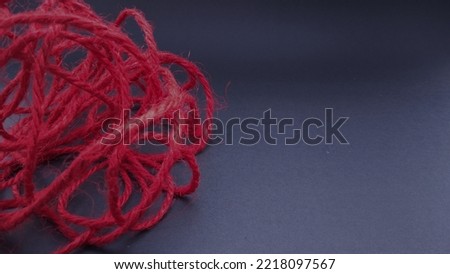 Negative space of 
Tangled red wool yarn on a dark background