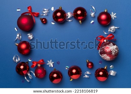 Christmas ball toys and confetti on color background, top view.