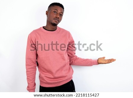 Portrait of handsome man wearing pink sweater over white background with arm out in a welcoming gesture.