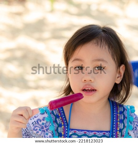 Portrait of pretty 4 years old cute baby Asian girl, little toddler child with beautiful bright eyes eat ice cream look at camera with copy space.
