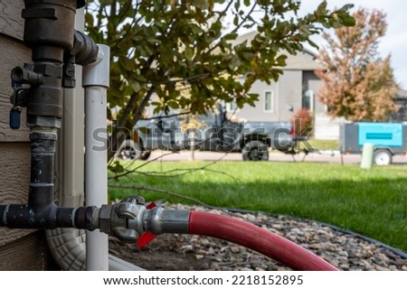Winterizing a residential irrigation system by using a compressor and forced air to blow the lines empty. Royalty-Free Stock Photo #2218152895