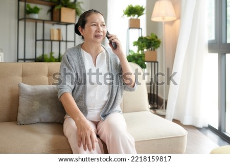 Worried senior woman sitting on couch when talking on phone