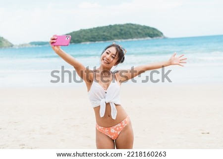 Portrait of happy smiling beautiful women taking a selfie photo on the beach. Pretty young Asian girl in casual looking clothes recording vlog video in bright sky