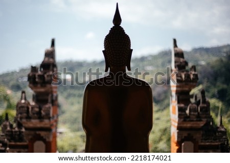 Silhouette of a buddha statue on the background of the balinese gate.