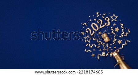 Festive Christmas and New Year background with golden champagne bottle, party decorations, confetti stars and 2023 numbers. Royalty-Free Stock Photo #2218174685