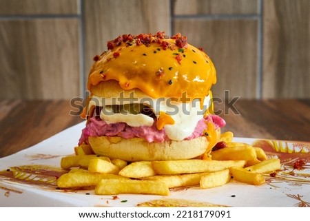 gourmet burger with meat, caramelized onion, tomato, bacon, french fries and dripping cheddar cheese