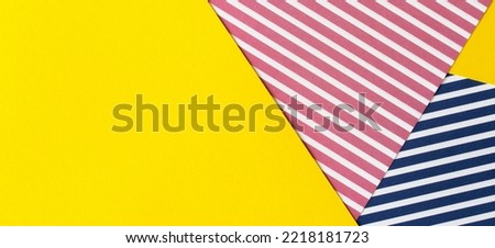 Abstract geometric fashion colored papers texture background. Striped paper with red, blue, white stripes and blank yellow paper background with copy space for text. Top view, flat lay