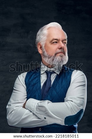 Portrait of aged businessperson dressed in waistcoat and white shirt posing with crossed arms.