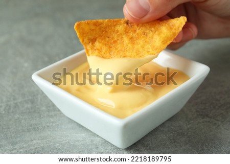 Female hand dips chip in cheese sauce, close up Royalty-Free Stock Photo #2218189795