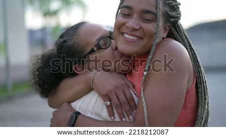 Brazilian adult daughter hugging senior mother showing love and affection. A caring black woman embracing older lady