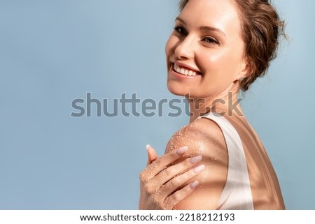 A beautiful tender woman put a natural cosmetic scrub to her shoulder and smiles Royalty-Free Stock Photo #2218212193