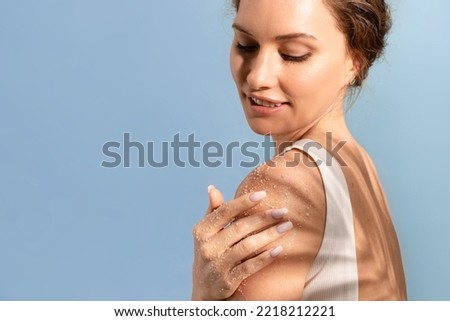 A beautiful attractive woman applies a cosmetic natural scrub to her shoulder and smiles Royalty-Free Stock Photo #2218212221