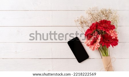 Happy birthday. Red gerbera daisy flowers and mobile phone on white wooden table, flat lay