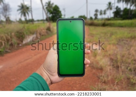 Phone with green screen or chroma key in the forest