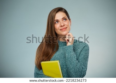Thinking positive woman holding yellow book. Advertising female studio portrait.