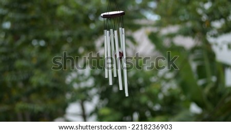 Wind Chimes hangs on the porch of the house against the backdrop of green trees Royalty-Free Stock Photo #2218236903