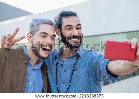 Young happy friends having fun taking selfie with mobile phone outdoor - Focus on left man face