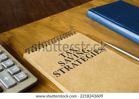 Notepad with tax savings strategies near a calculator. Royalty-Free Stock Photo #2218243609