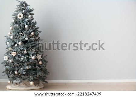 Christmas tree with glowing lights and decor near light wall
