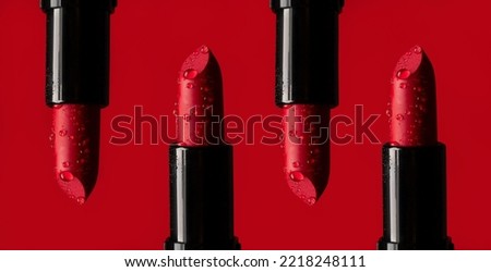 close-up on four red lipsticks in splashes of water on a red background