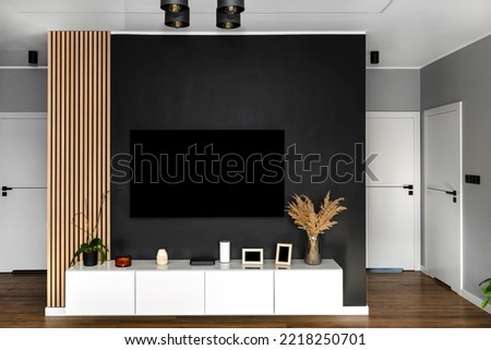Black matte TV wall in the living room with a hanging TV set over a white wall unit.