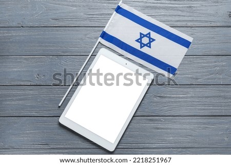 Flag of Israel and tablet computer on grey wooden background