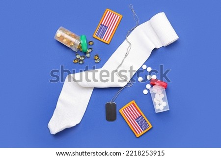 Chevrons of USA army, jars with pills, bandage and military tag on blue background