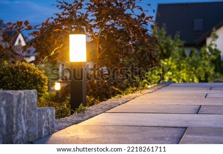 Closeup of Garden Bollard Lamp Installed Along the Walkway in Landscaped Backyard Garden. Evening Time. Outdoor Lighting Theme.