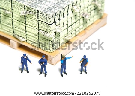 Miniature people toy figure photography. Money transfer security concept. A police officer standing in front of money cargo pallet. Isolated on grey background. Image photo