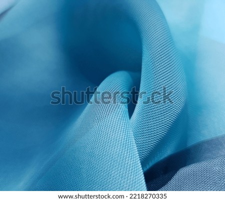 Wave turquoise blue transparent fabric;
two twisted folds (macro, texture).
 Royalty-Free Stock Photo #2218270335