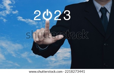 Businessman pressing 2023 start up business flat icon over blue sky with white clouds, Business happy new year 2023 cover concept