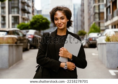 Brunette young woman wearing jacket standing with laptop at city street Royalty-Free Stock Photo #2218278701