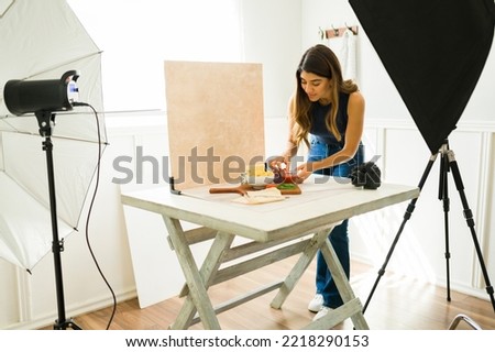 Hispanic food photographer smiling while doing food styling and getting ready for a photo shoot at the professional studio 