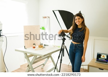 Beautiful happy woman photographer smiling while working doing a professional photo shooting at the studio