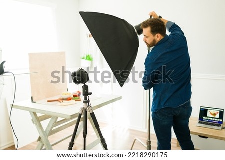 Photographer at the studio adjusting the monolight softbox and preparing to take professional photo with good lighting