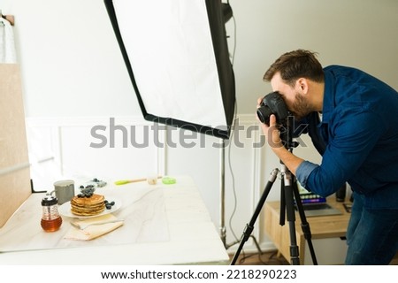 Caucasian photographer doing a professional shooting and taking pictures of food at the studio using good lighting