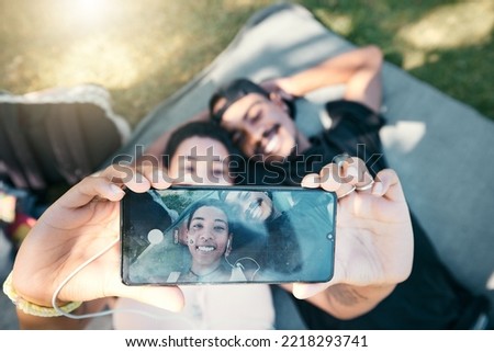Couple in park, phone selfie and lying on blanket to relax on romantic picnic and spending quality time together. Love, romance and man and woman on grass with picture on smartphone screen and smile.