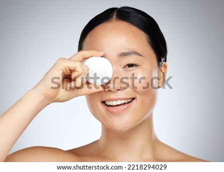 Skincare, beauty and woman with a cotton pad for cleaning, wellness and facial health against grey mockup studio background. Portrait of happy, relax and face of Asian model with smile for cosmetics