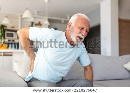 Senior elderly man touching his back, suffering from backpain, sciatica, sedentary lifestyle concept. Spine health problems. Healthcare, insurance Royalty-Free Stock Photo #2218296847