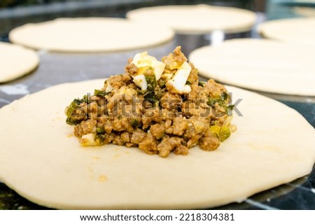 Preparation of a pastry with puff pastry and minced meat stuffing with chopped boiled egg, onion, garlic and green seasoning. Mention food preparation in the kitchen at home, fast and practical food.