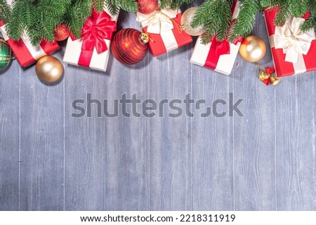 Present Boxes With Christmas tree on wooden background. Various red and white gifts with festive ribbon, fir tree branches and Xmas decoration on old grey plank timber background top view copy space