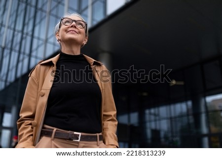 portrait of a successful mature adult charismatic female leader against the backdrop of a glass facade of an office building, business economic consultant concept Royalty-Free Stock Photo #2218313239