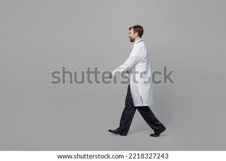 Side profile view full body male confident doctor man wears white medical gown suit work in hospital walking going isolated on plain grey color background studio portrait. Healthcare medicine concept Royalty-Free Stock Photo #2218327243