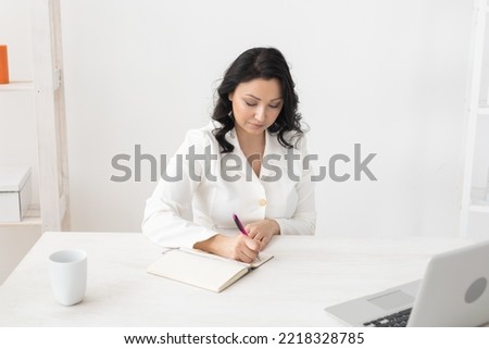 Indian woman beautician takes notes in office - cosmetologist business woman or doctor concept