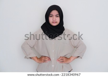 Asian young girl wearing hijab showing unhappy expression with both hands on her waist